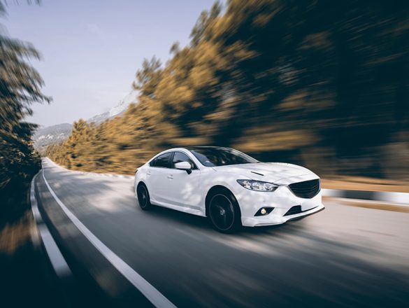 White car speed driving on asphalt road at daytime
